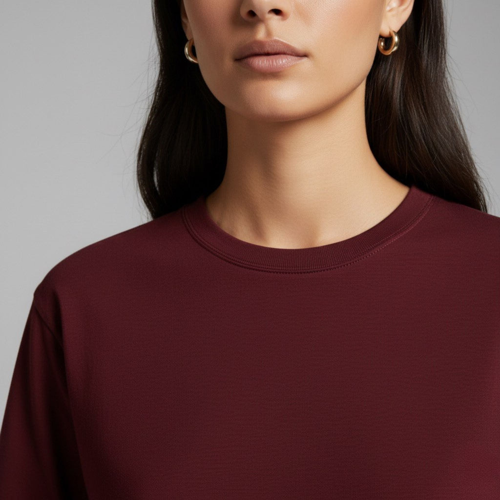 Close-up of a person wearing a moleculuxe bordeaux burgundy sweater against a gray background