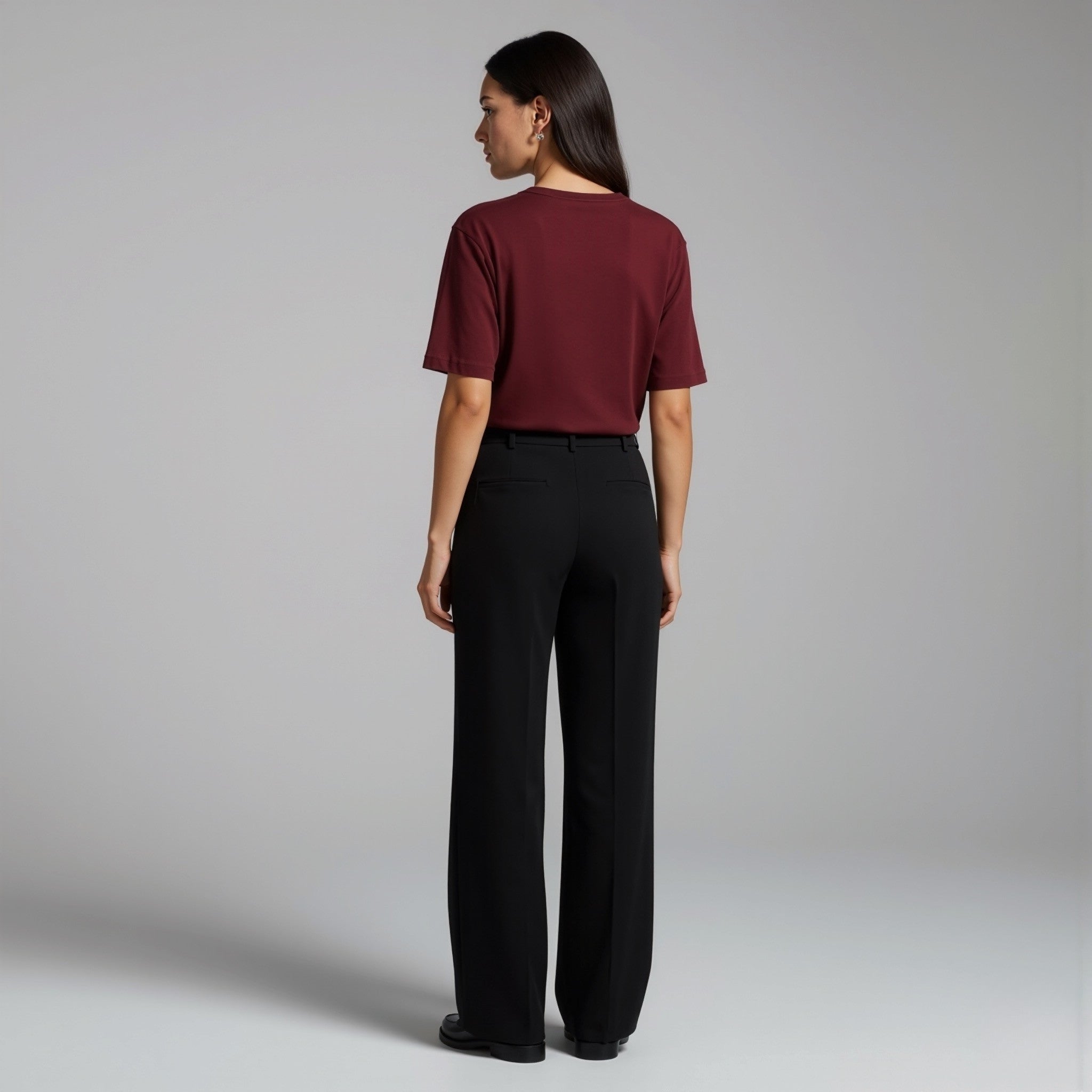 Person wearing a moleculuxe bordeaux burgundy top and black pants on a plain background