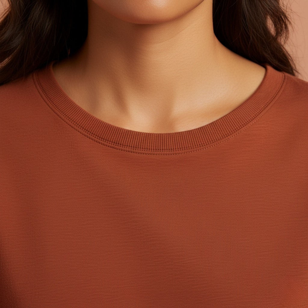 Close-up of a person wearing a moleculuxe burnished copper brown sweatshirt with a neutral background