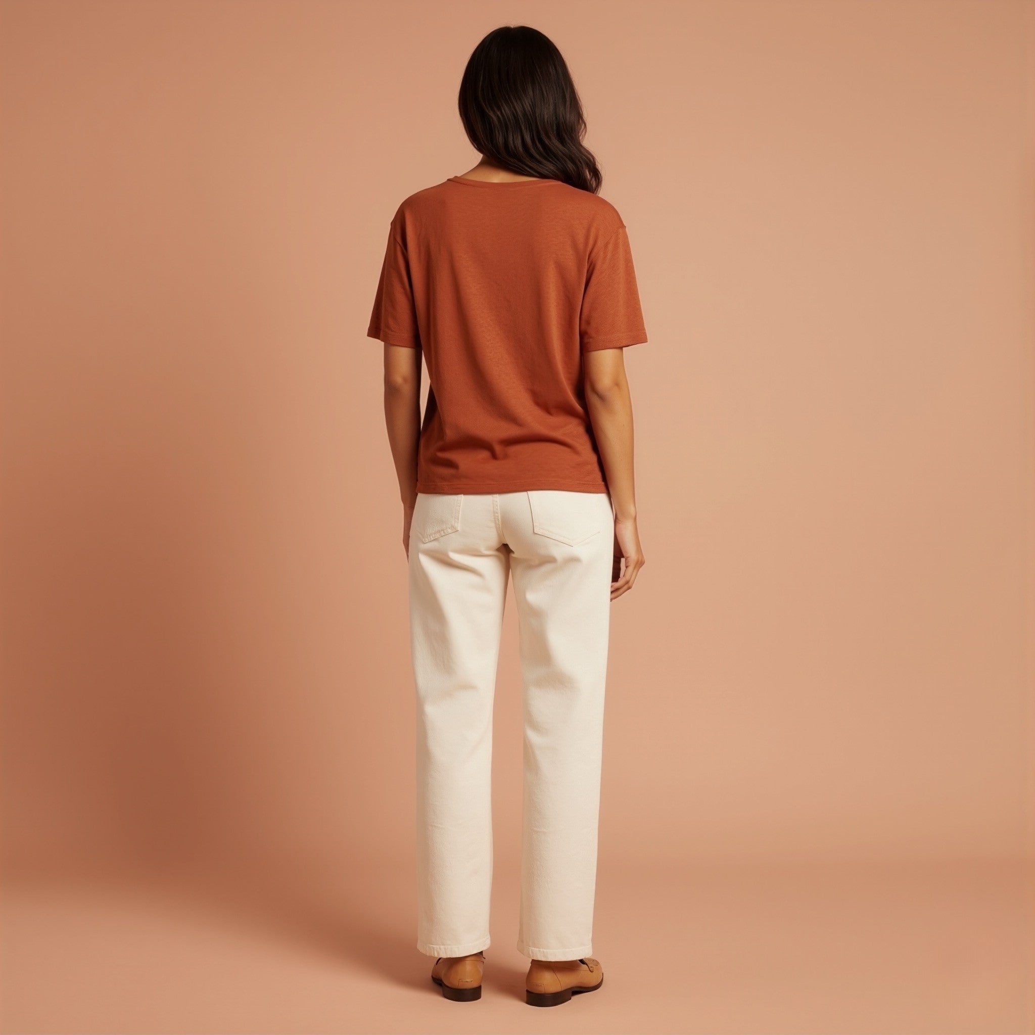 Person wearing a moleculuxe burnished copper brown shirt and white pants against a beige background