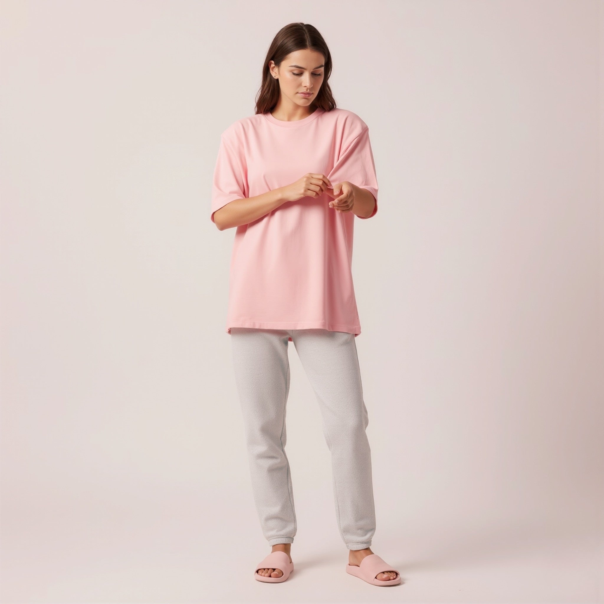 Woman wearing a moleculuxe Blush Whisper pink oversized t-shirt and light gray pants on a plain background
