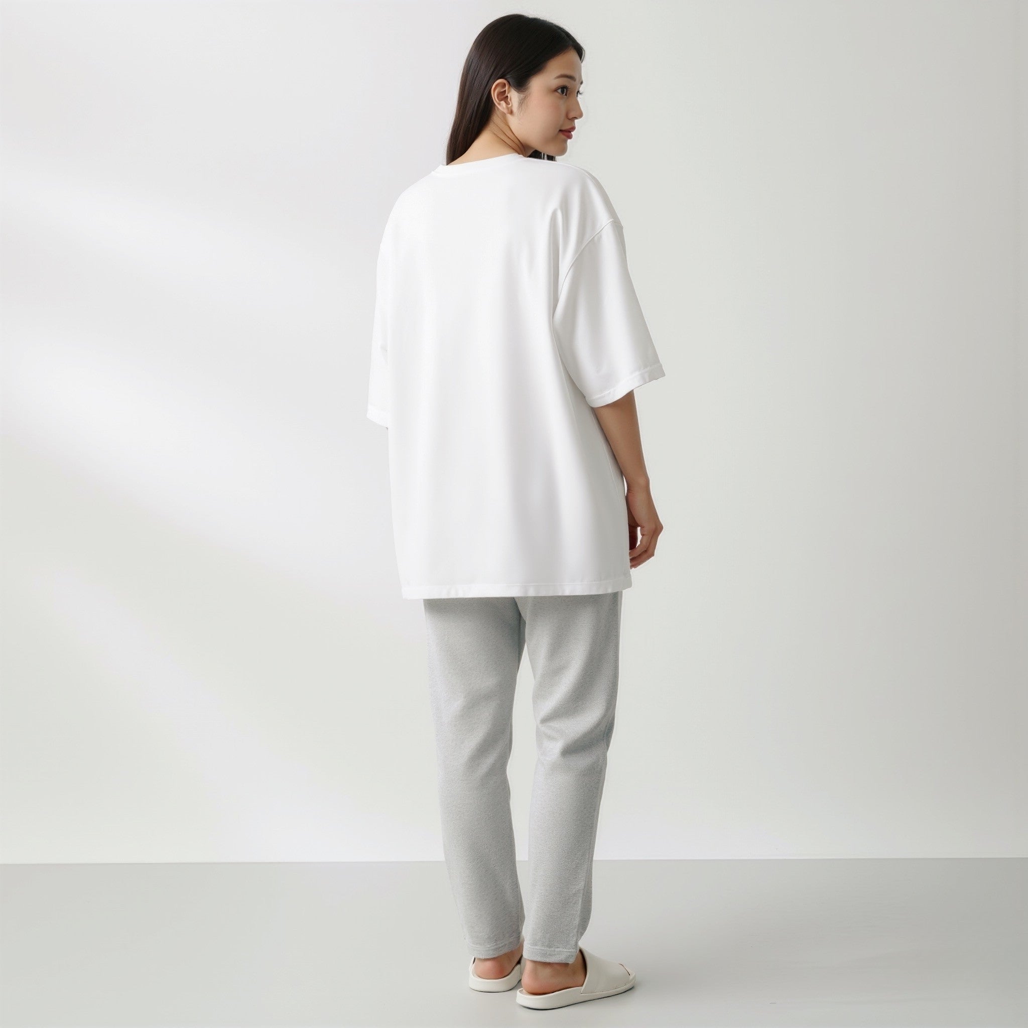 Person wearing a moleculuxe pristine white oversized shirt and gray pants on a plain background