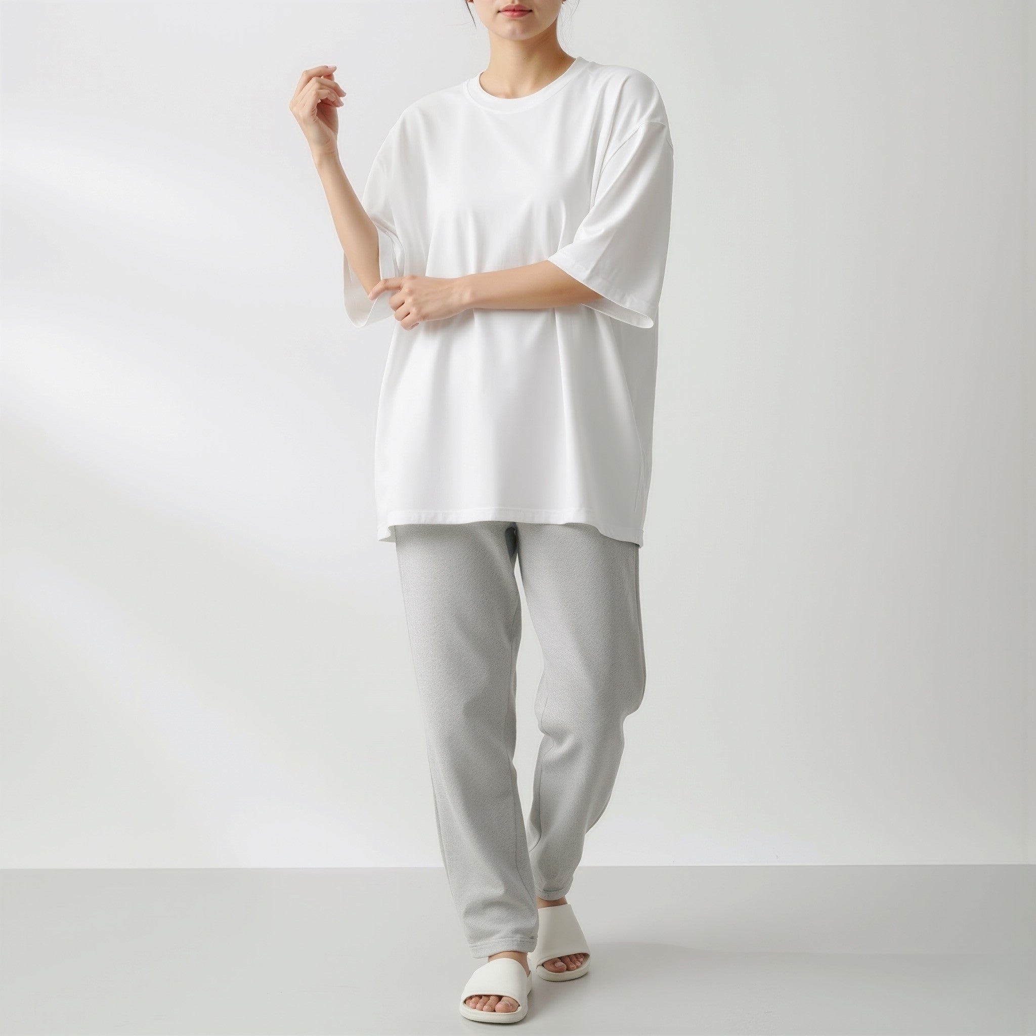 Person wearing a moleculuxe pristine white oversized shirt and light gray pants on a white background