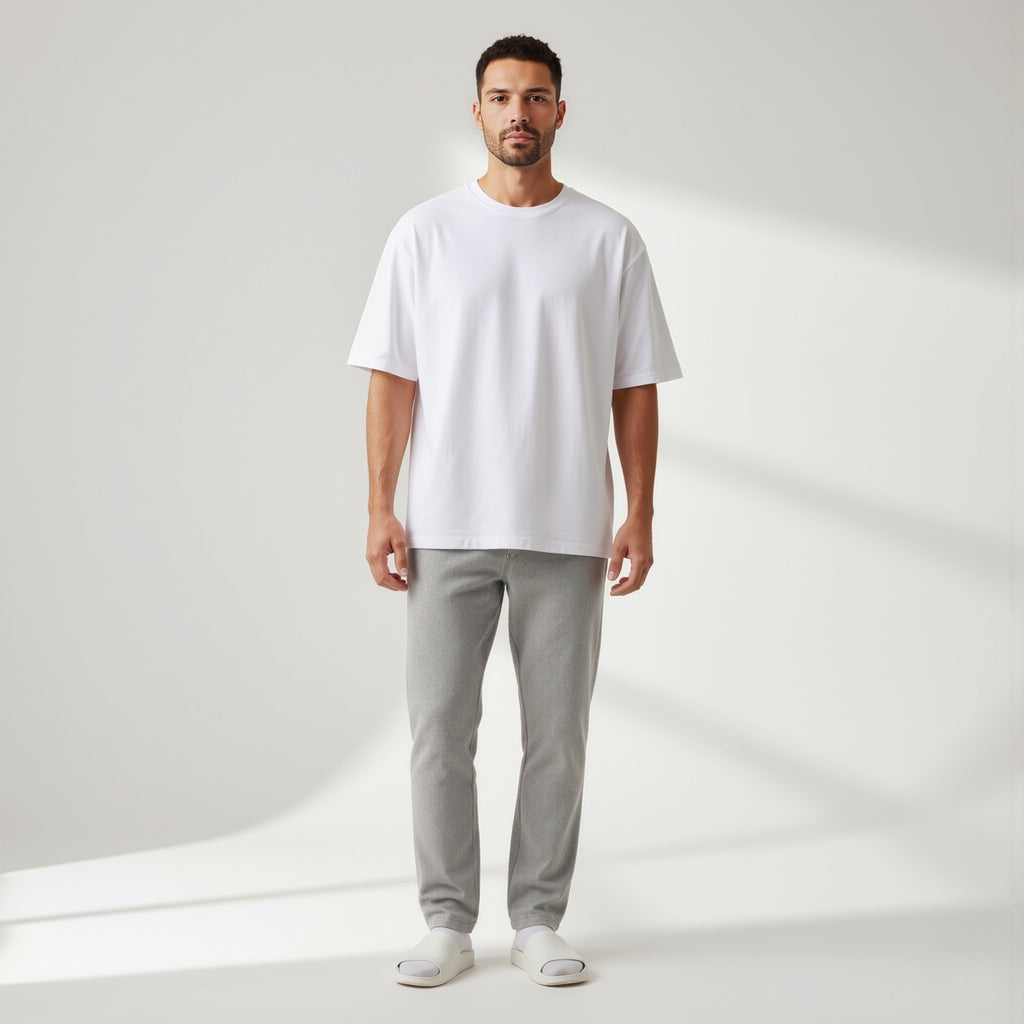 Man wearing a moleculuxe pristine white t-shirt and gray pants on a plain background