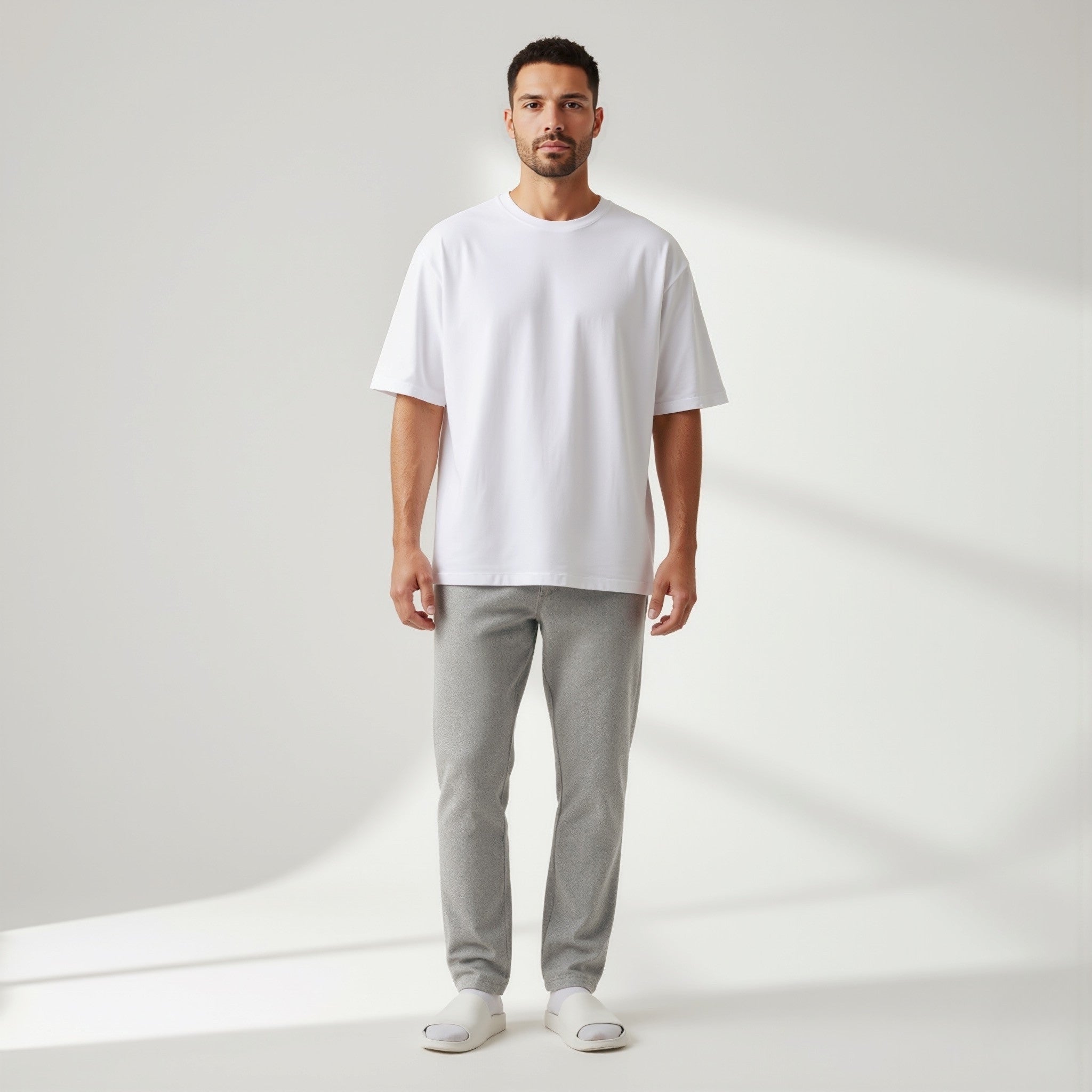 Man wearing a moleculuxe pristine white t-shirt and gray pants on a plain background
