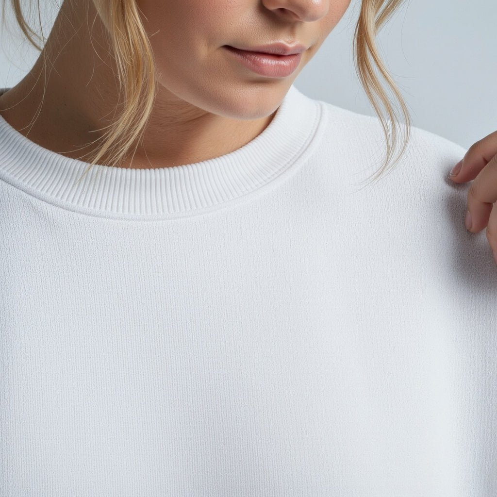Close-up of a person wearing a plain moleculuxe pristine white sweater against a light gray background