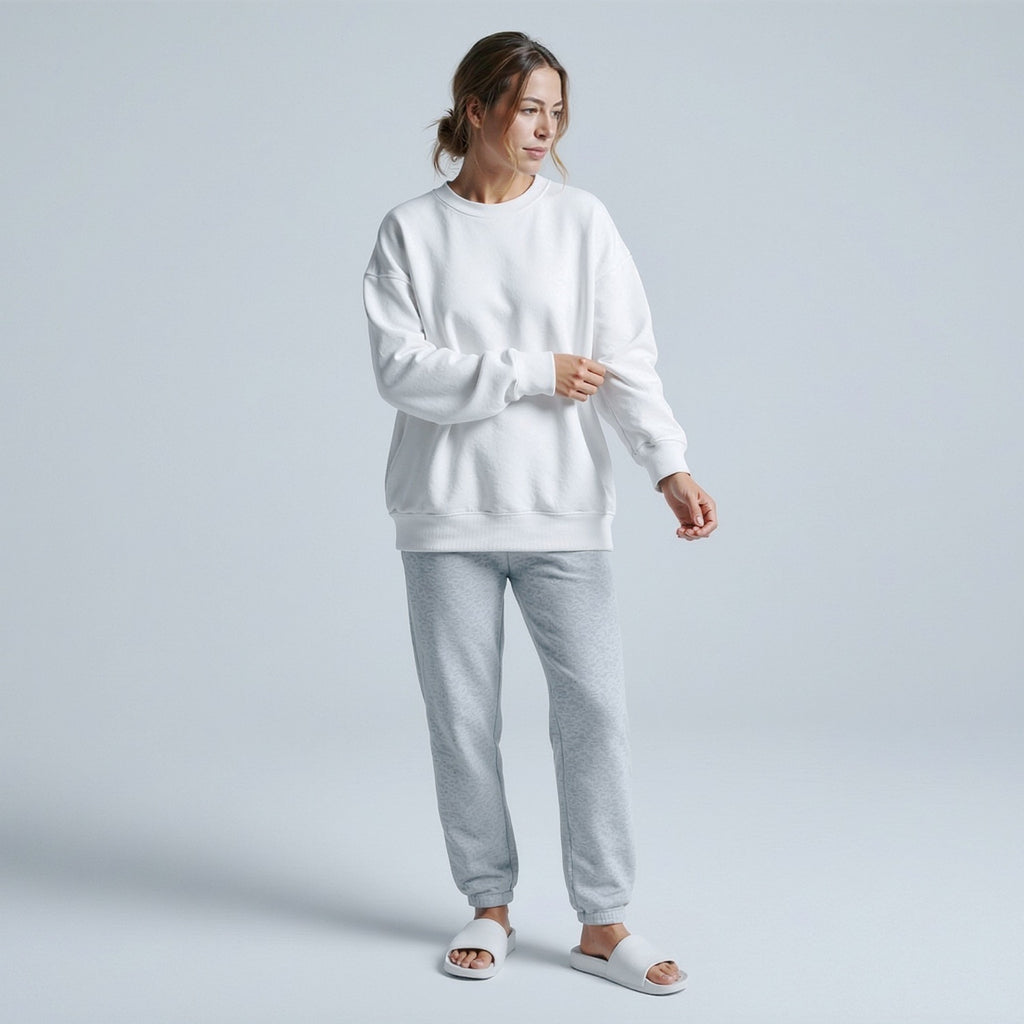 Woman wearing a moleculuxe pristine white sweatshirt and gray pants on a light gray background