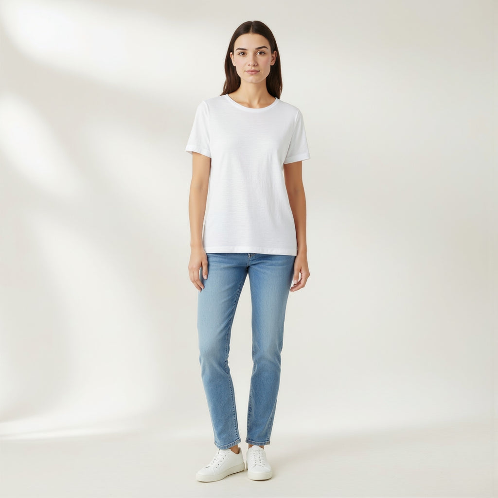 Person wearing a moleculuxe pristine white t-shirt and light blue jeans on a plain background