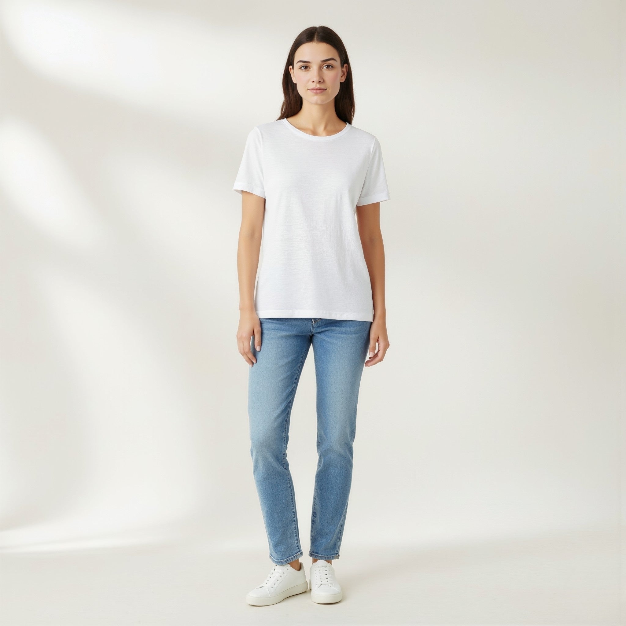 Person wearing a moleculuxe pristine white t-shirt and light blue jeans on a plain background