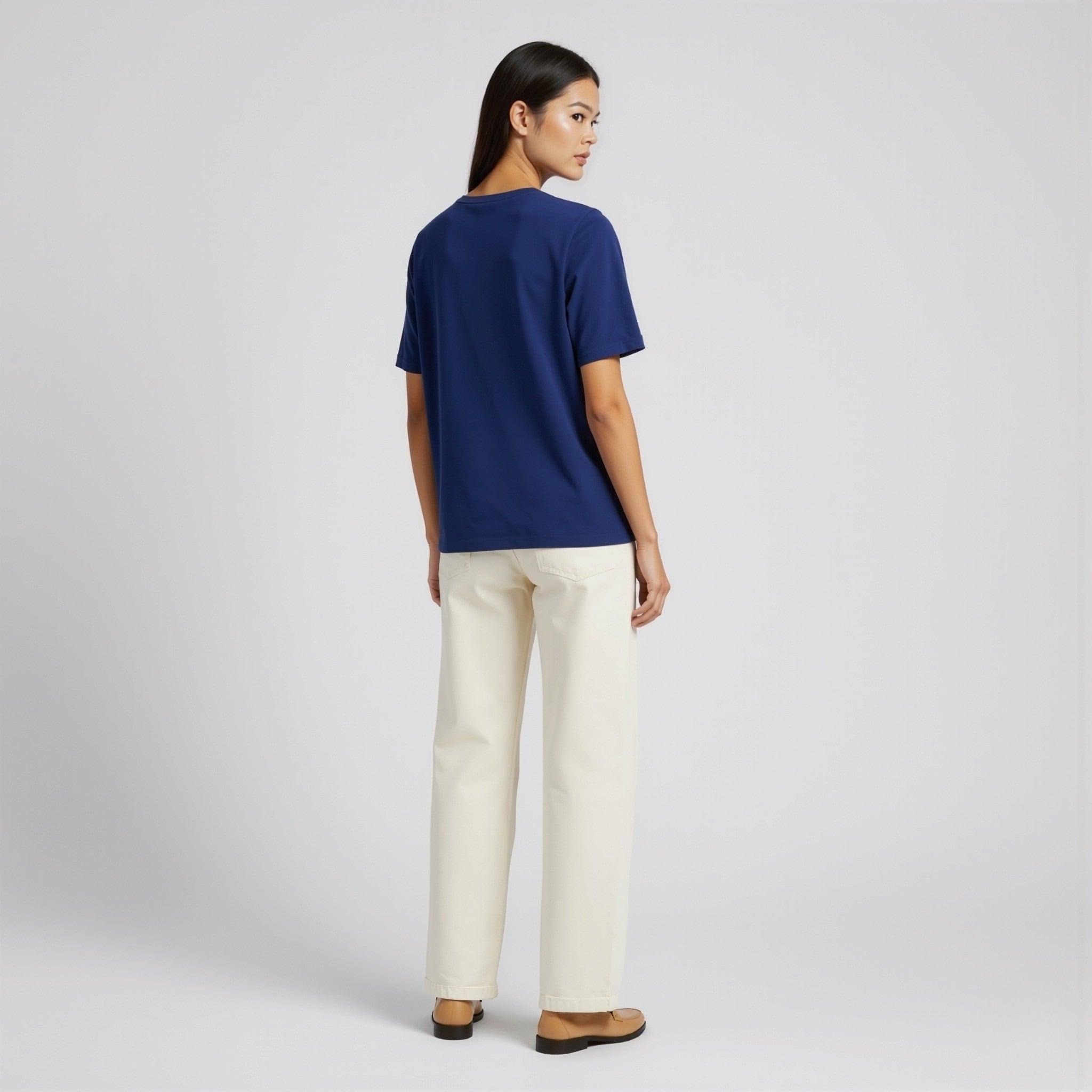 Woman wearing a moleculuxe Sapphire Majesty blue shirt and white pants on a light gray background