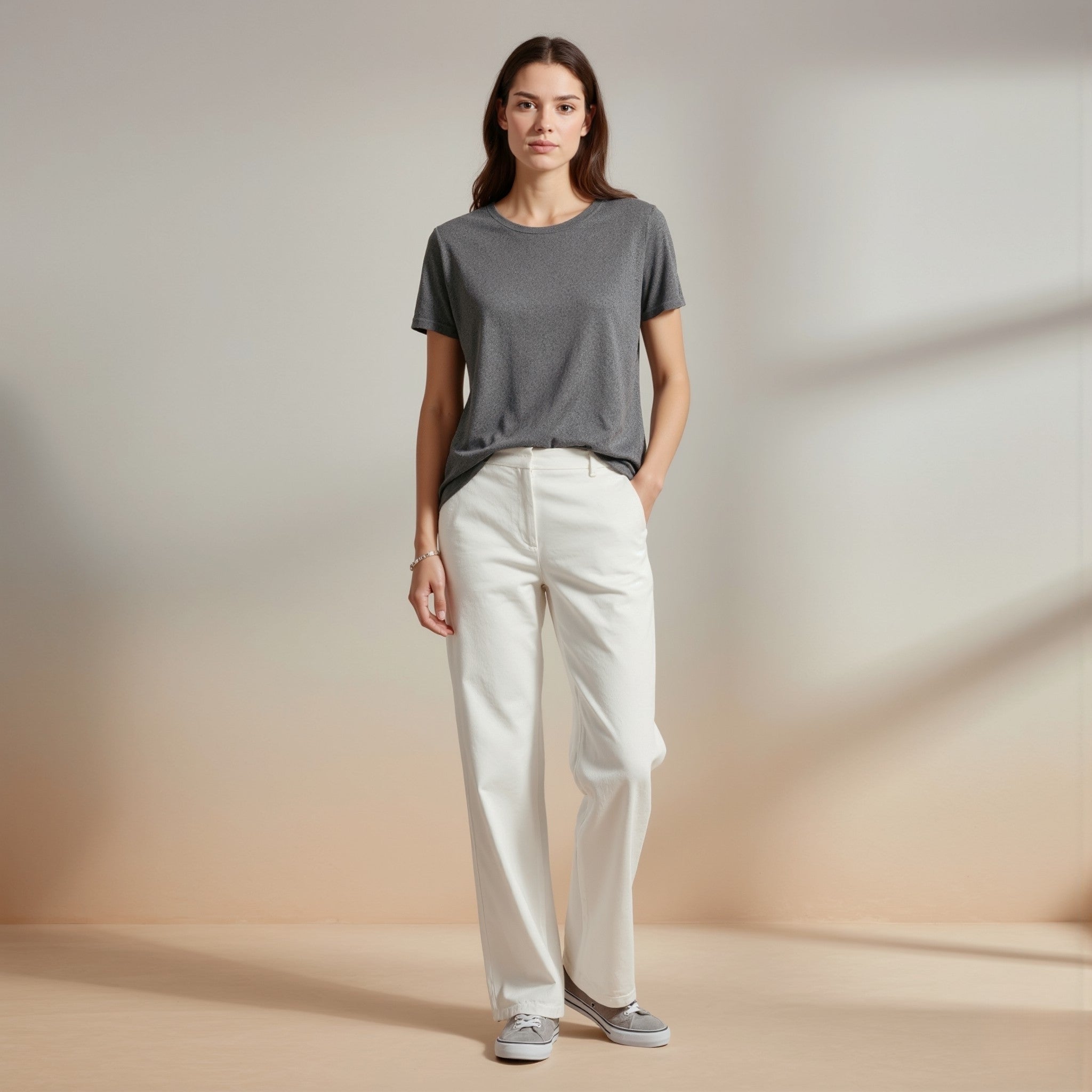 Woman wearing a moleculuxe smoky quartz gray t-shirt and white pants against a neutral background