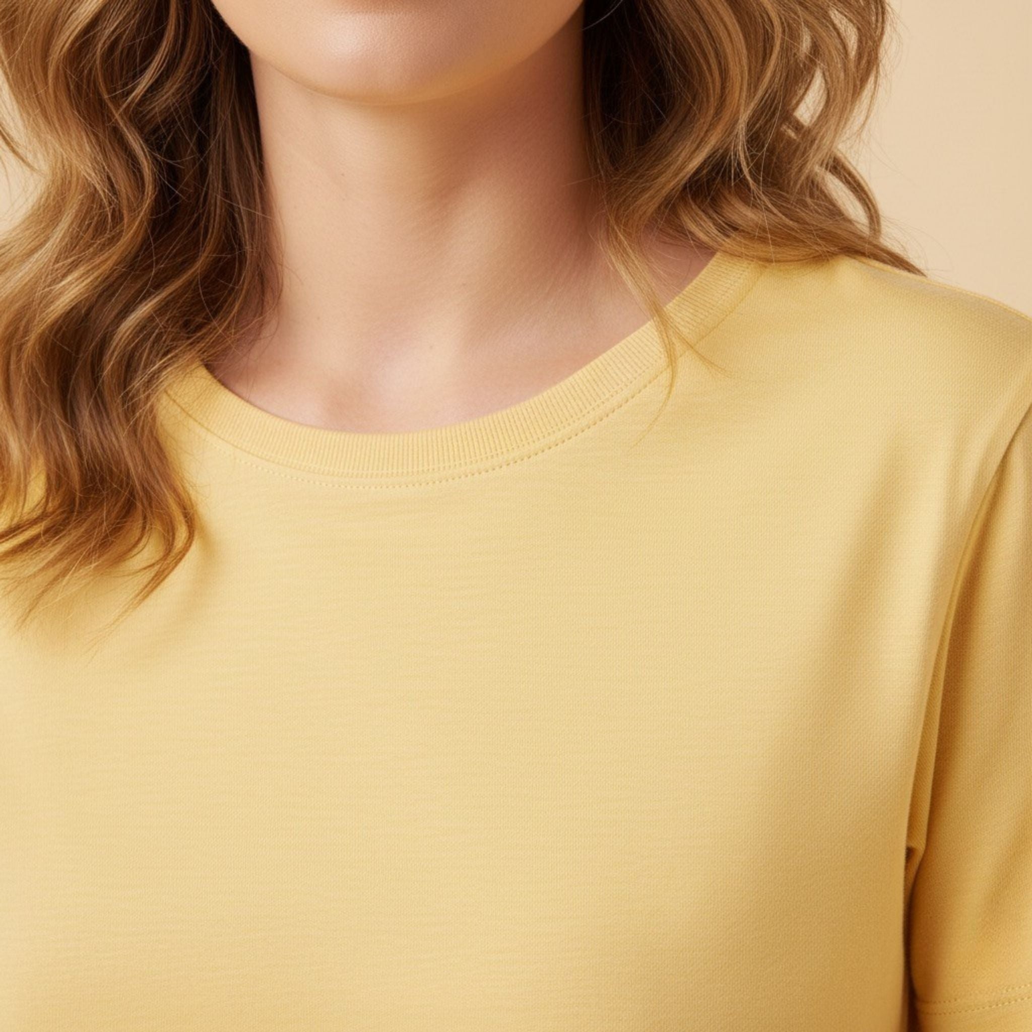 Close-up of a person wearing a moleculuxe soft sunflower yellow long-sleeve shirt with a neutral background