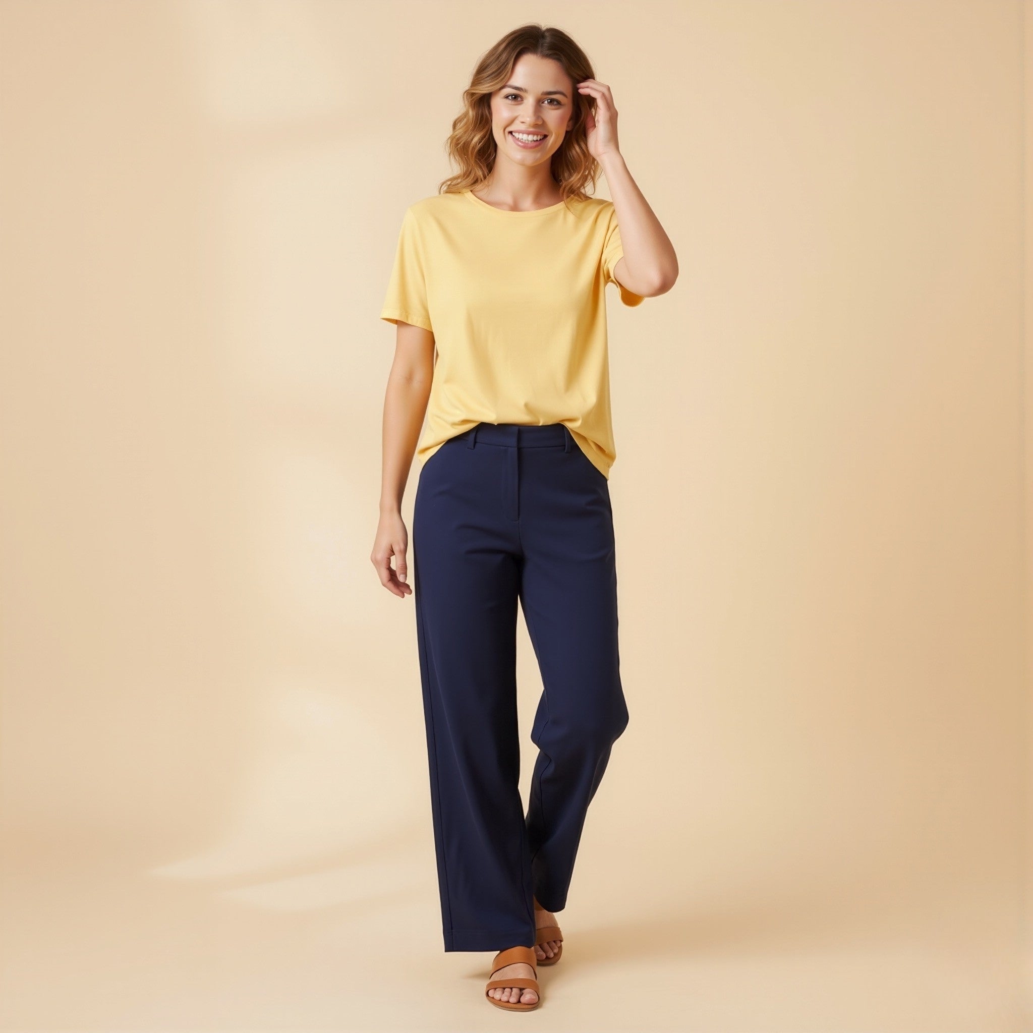 Woman wearing a moleculuxe soft sunflower yellow top and navy pants on a beige background