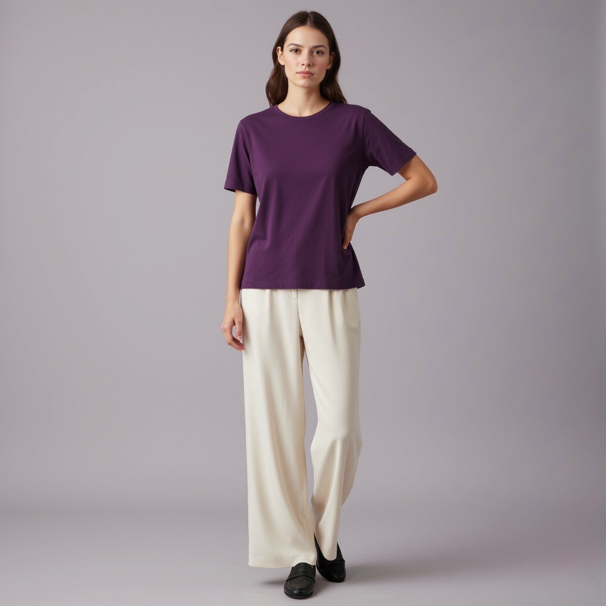 Woman wearing a moleculuxe imperial violet purple t-shirt and white pants against a gray background