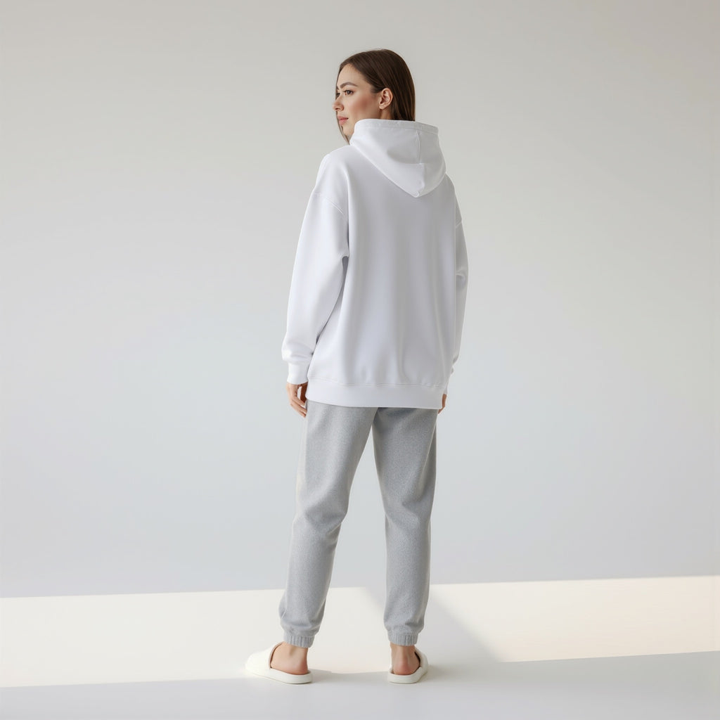 Person wearing a moleculuxe pristine white hoodie and gray pants set on a plain background